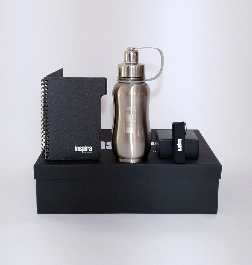 La foto presenta un kit hecho para la marca de diseño Inspira compuesta por un termo metálico con grabado láser, una libreta impresa a 1 tinta y un usb.